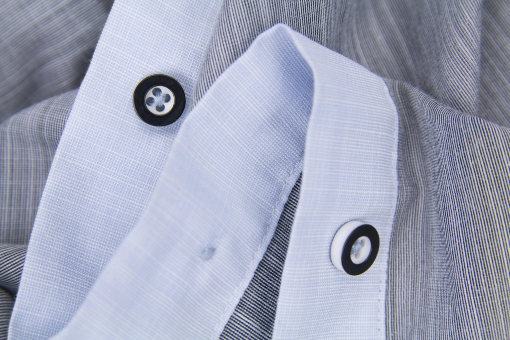 Detailed close-up of black and white buttons on a striped shirt showcasing fabric texture.
