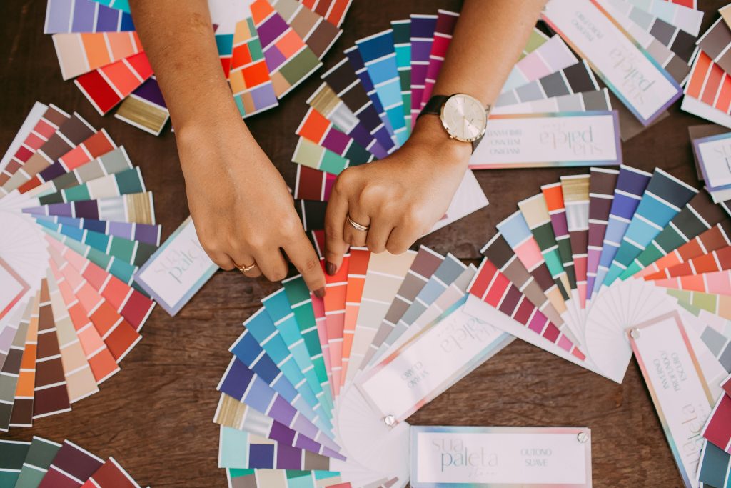 Hands examining colorful fabric swatches on a table, highlighting design choices.